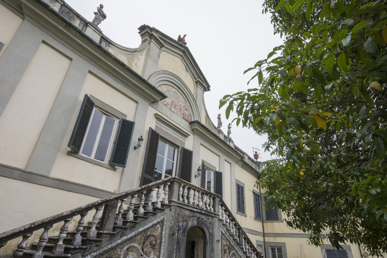 The villa's carved tympanum above its double staircase, in soft sepia-graphite tone